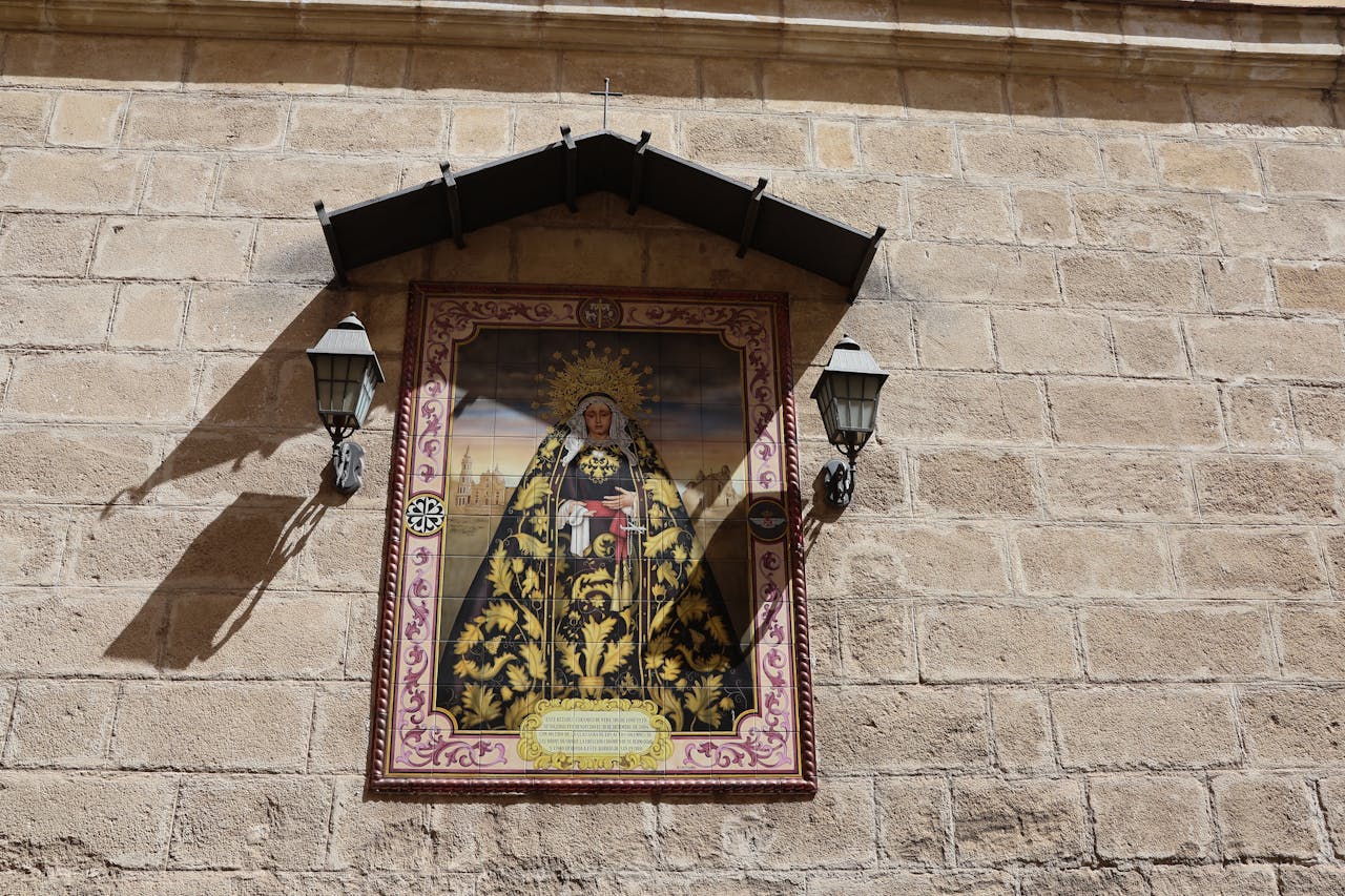 Beautiful religious artwork displayed on a stone wall in Jerez de la Frontera, Spain.